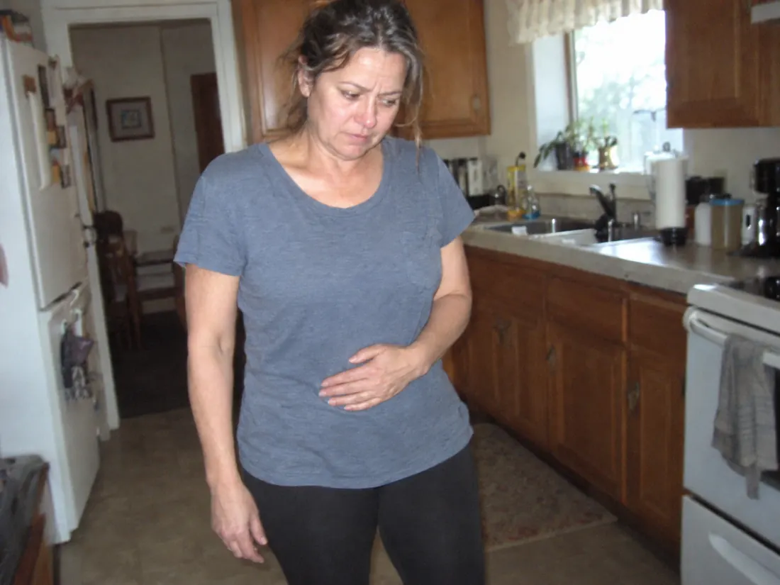 Woman standing in her kitchen with a hand on her stomach